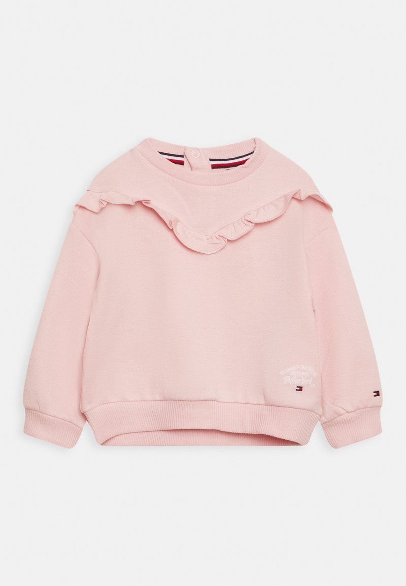Jasnoróżowy sweatshirt dla malucha z falbaną na klatce piersiowej, ściślejszymi mankietami i zapięciem na nap przy karku.