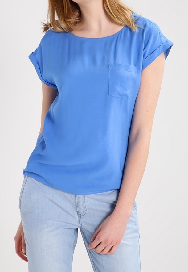 Svetle modrá halenka s krátkým rukávem vyrobená z hladkého materiálu, s kulatým výstřihem a kapsičkou na levé straně.