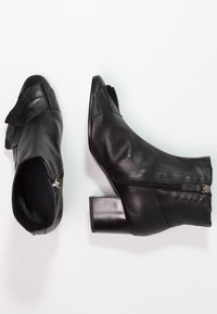 Bottes basses en cuir noir avec un talon bloc bas, un bout pointu, une fermeture éclair latérale et un mélange de panneaux lisses et texturés.