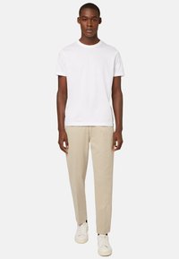 White cotton t-shirt, beige cotton chinos, and white sneakers. Simple design, relaxed fit, with short sleeves and standard crew neck.