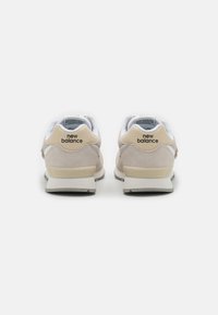 Baskets en daim beige clair avec des accents en maille blanche. Comprend un logo crème au talon et une semelle texturée pour l'adhérence.