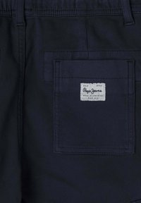 Tmavomodré nohavice so zadnou vreckom, na ktorom je našitý štítok s nápisom "Pepe Jeans." Hladká textura s jednoduchým dizajnom.
