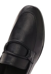 Mocassini in pelle nera con punta arrotondata, caratterizzati da un vamp cucito e una fascetta decorativa sulla parte frontale. Texture liscia con dettagli minimi.