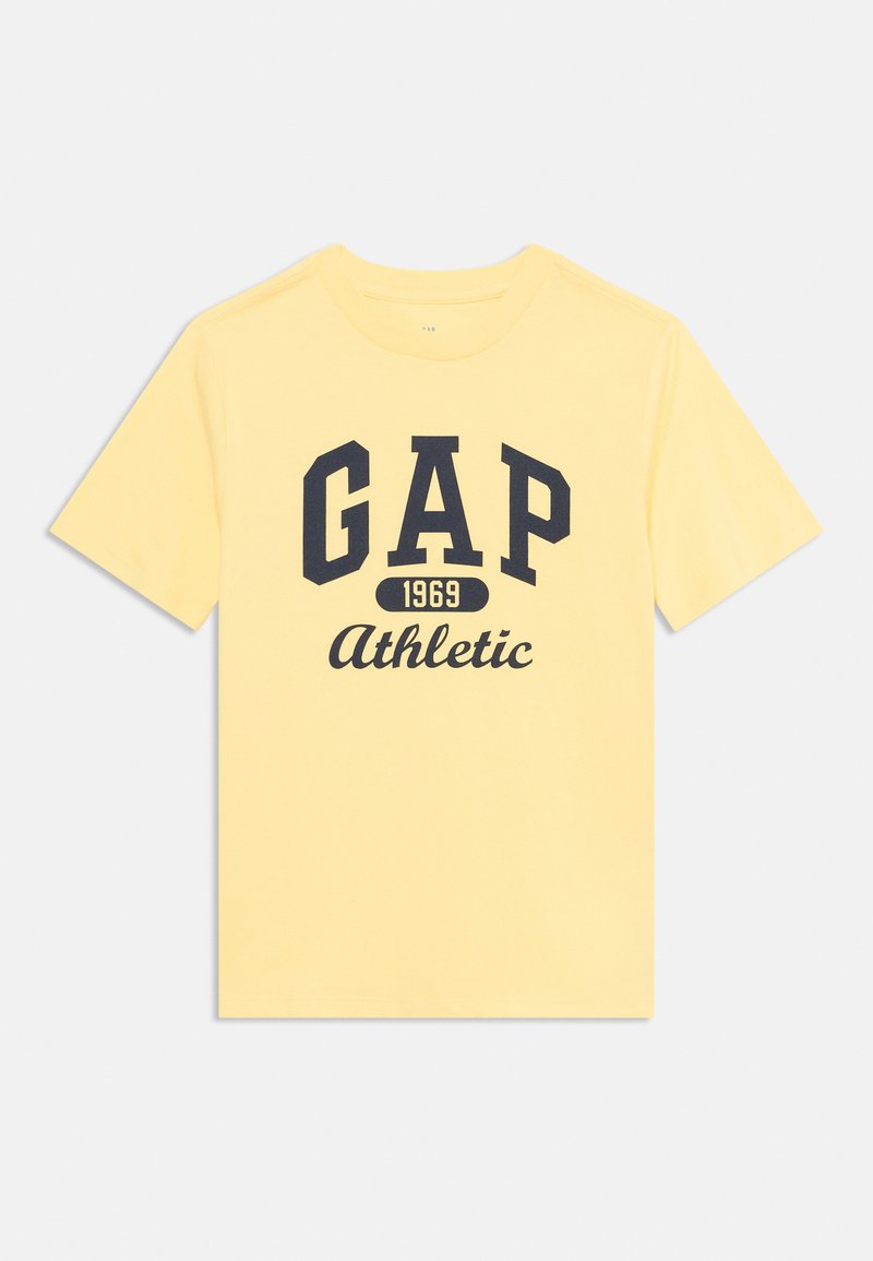Gul bomull T-skjorte med korte ermer. Har fet marineblå tekst "GAP", "1969," og "Athletic" i kursiv i midten.