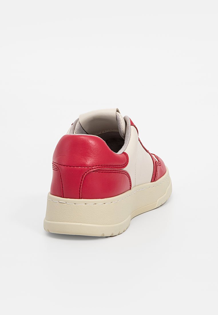 Zapatilla de cuero roja y crema con un collar acolchado, detalles texturizados y una suela gruesa en color blanco roto. Presenta costuras a lo largo de los paneles laterales.