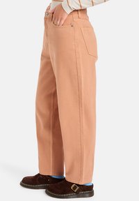 Pantalones de color durazno, de corte holgado y cintura alta, elaborados con denim resistente. Presentan bolsillos frontales y costuras en contraste.