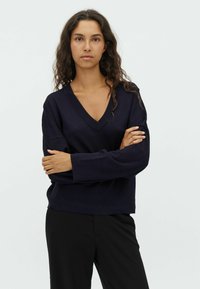 Dark navy knitted sweater with a V-neck, relaxed fit, and long sleeves. Smooth texture, minimalistic design, ideal for layering.