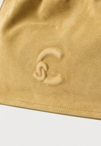 Borsa in suede di colore marrone chiaro con una texture morbida. Presenta un logo impresso e cuciture precise lungo il bordo.
