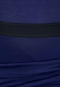 Námorní tkanina s hladkou texturou má vodorovný černý pruh uprostřed, což vytváří výrazný designový prvek.