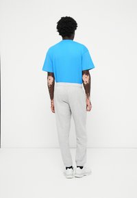 Blå bomulds t-shirt med korte ærmer, parret med lys grå sweatpants. Begge beklædningsgenstande har en afslappet pasform og elastisk talje.