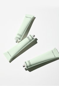 Drie mintgroene tubes met crème met zilveren schroefdoppen, voorzien van minimaal tekstlabels en een gladde textuur, gerangschikt op een witte ondergrond.