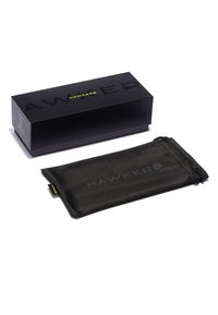 Fekete téglalap alakú doboz, rajta a "HAWKERS" felirat, hozzá illő fekete mikroszálas tasakkal, melyen dombornyomott logó és húzózsinóros záródás található.