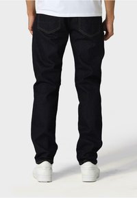 Temno modri džinsi slim kroja, z dvema zadnjima žepoma, rumenimi šivi in klasičnim ravnim krojem.