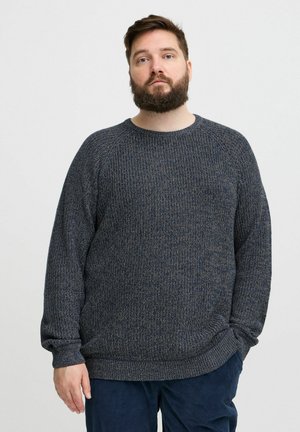 Pulover tricotat navy cu un model texturat, decolteu rotund și manșete și tiv ribbate. Asortat cu pantaloni din catifea întunecată.