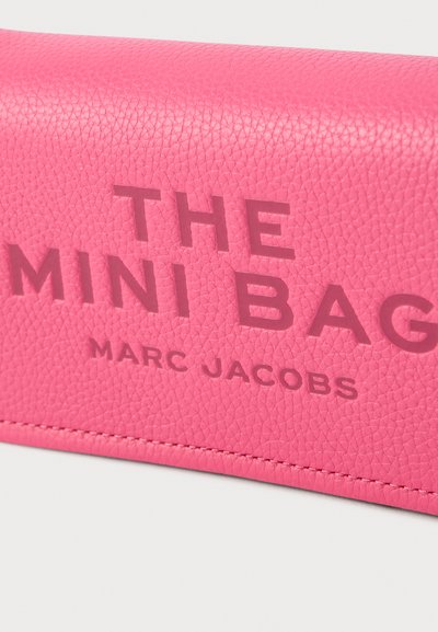 Vaaleanpunainen teksturoitu nahkainen minilaukku, jossa kohopainettu teksti "THE MINI BAG" ja "MARC JACOBS" vastaavalla värillä. Sauman varressa kirjailtu yksityiskohta.