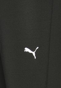 Pantaloni sportivi neri con una trama liscia, caratterizzati da un logo di puma bianco che salta sul lato sinistro e un dettaglio con cucitura verticale.