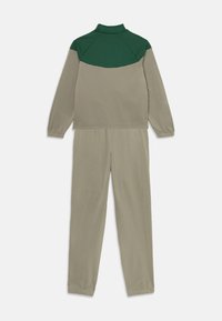 Track suit su aukštu apykakle, spalvotai blokiniu dizainu, žalia viršutinė dalis ir šviesiai ruda apatinė dalis, pagaminta iš lygaus audinio, elastingais rankogaliais ir juosmeniu.