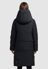 Sort pufferjakke med hætte, der har et quiltet design, mellemlang længde og en lille logo detalje nær kanten. Glat, vandafvisende materiale.