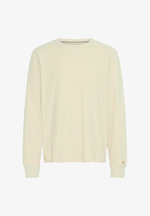 Kreminės spalvos ilgomis rankovėmis marškinėliai, pagaminti iš minkštos medvilnės. Turi susikirtusį apykaklės ir rankogalių dizainą, o apačioje yra mažas logotipas.