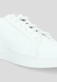 Białe skórzane sneakersy z okrągłym noskiem, płaskimi białymi sznurówkami i minimalnymi detalami przeszyć. Gładka faktura i czysty, prosty design.