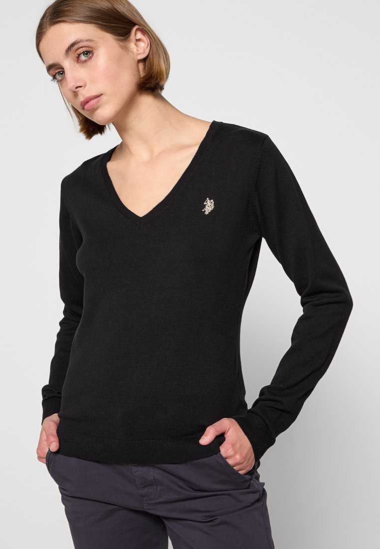 Pull noir en V en tissu tricoté doux. Présente des manches longues et un petit logo sur la poitrine gauche. Coupe classique.