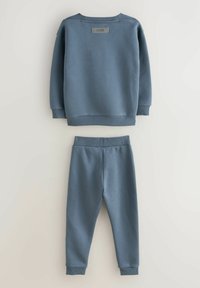 Blauer Baumwoll-Sweatshirt mit gerippten Bündchen und Kragen, mit einem Etikett auf der Rückseite. Passende blaue Baumwoll-Jogginghose mit elastischem Bund.