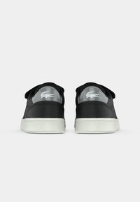 Sneakers neri con materiale testurizzato, forma arrotondata, suola in gomma bianca e un accento grigio sul tallone con un piccolo logo.