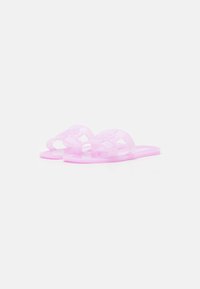 Rosa genomskinliga plasttofflor med två korsande remmar och platta sulor. Har ett geometriskt mönster på remmarna för extra textur.