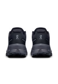 Chaussures de sport noires au design épuré, dessus en tissu texturé et semelles rembourrées. Présente un logo sur le talon et des accents réfléchissants.