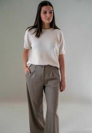 Witte gebreide top met korte mouwen, gecombineerd met high-waisted lichtgrijze broek met knoopsluiting en plooien, met een gladde stofstructuur.