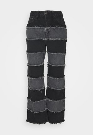 Jean taille haute à jambes larges avec des panneaux horizontaux alternés en denim noir et gris foncé et des bords effilochés sur chaque panneau.