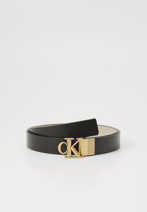 Must mustrih, millel on kuldse tooni klamber ja "CK" logo. Sujuv tekstuur, reguleeritav pikkus, lame disain.