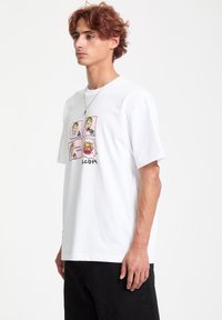 Hvid bomulds T-shirt med en farverig tegneserie grafik med fire firkanter og legende tekst. Løs pasform, korte ærmer og rund hals design.