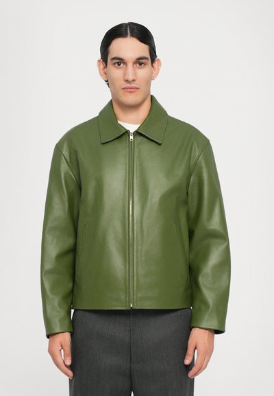 Green leather jacket with a collar, front zipper, and side pockets. Features a smooth texture and a boxy, relaxed fit.