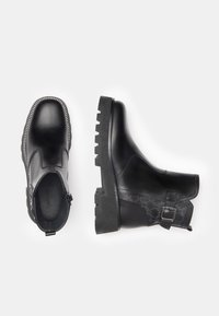 Black ankle boots with smooth leather surface, textured detailing, side zipper, chunky rubber sole, and decorative buckle accent.