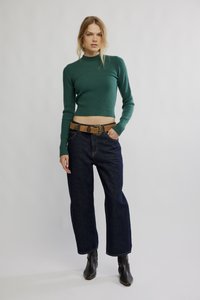 Grønn ribbestrikket cropped genser, mørkeblå vide jeans, og et brunt lærbelte med dekorativt spenne. Svarte ankelstøvler.