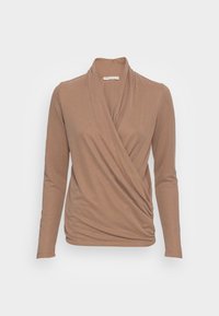 Langärmlige Wickelbluse in Hellbraun, aus weichem Stoff mit gerafftem Detail an der Taille und einem lockeren Kragen. Flache Nähte, keine Muster oder Akzente.