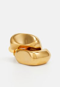 Anello astratto color oro con forme morbide e arrotondate, caratterizzato da una finitura lucida e leggere variazioni nel contorno.