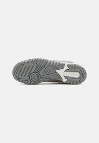 Gray athletic shoe sole featuring a textured rubber design with zigzag patterns, brand logo, and contoured shape for traction.