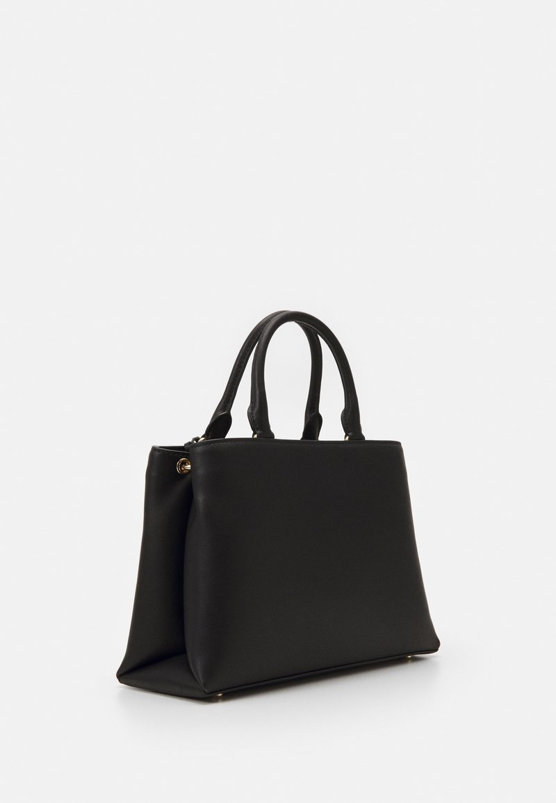 Musta tekonahkainen käsilaukku, jossa on kaksi pyöreää kahvaa, jämäkkä muoto ja kultaiset metalliosat. Sileä pinta ja siistit linjat.