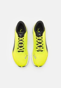 Zapatillas de correr verde lima con detalles en negro, parte superior de punto texturizado y cierre de cordones. Incluye un logotipo plateado y suela de goma para mayor tracción.