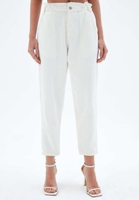 Weiße Jeans mit geradem Schnitt, einem hohen Bund, Gürtelschlaufen und dezenten Nähten. Mit einem Knopfverschluss auf der Vorderseite akzentuiert.