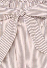 Tissu beige rayé avec de fines lignes blanches, comportant un détail de nœud noué à la taille et une ceinture élastique froncée pour un look ajusté.