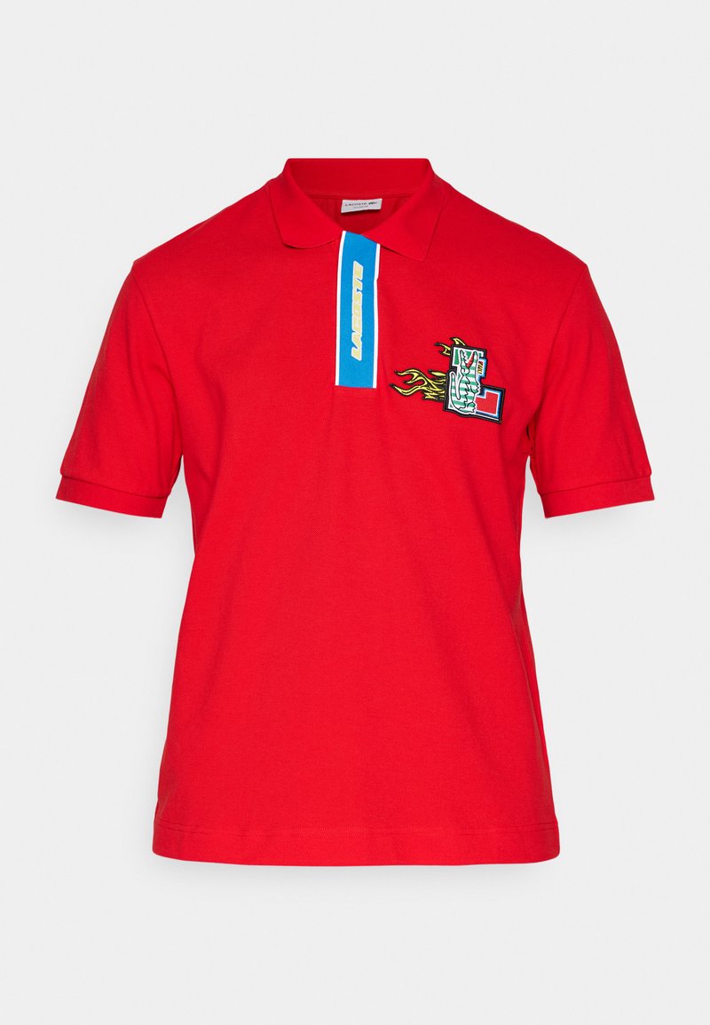 Polo rouge en coton, avec un col bleu contrastant portant un logo, un graphique brodé avec des flammes sur la poitrine et des manches courtes.