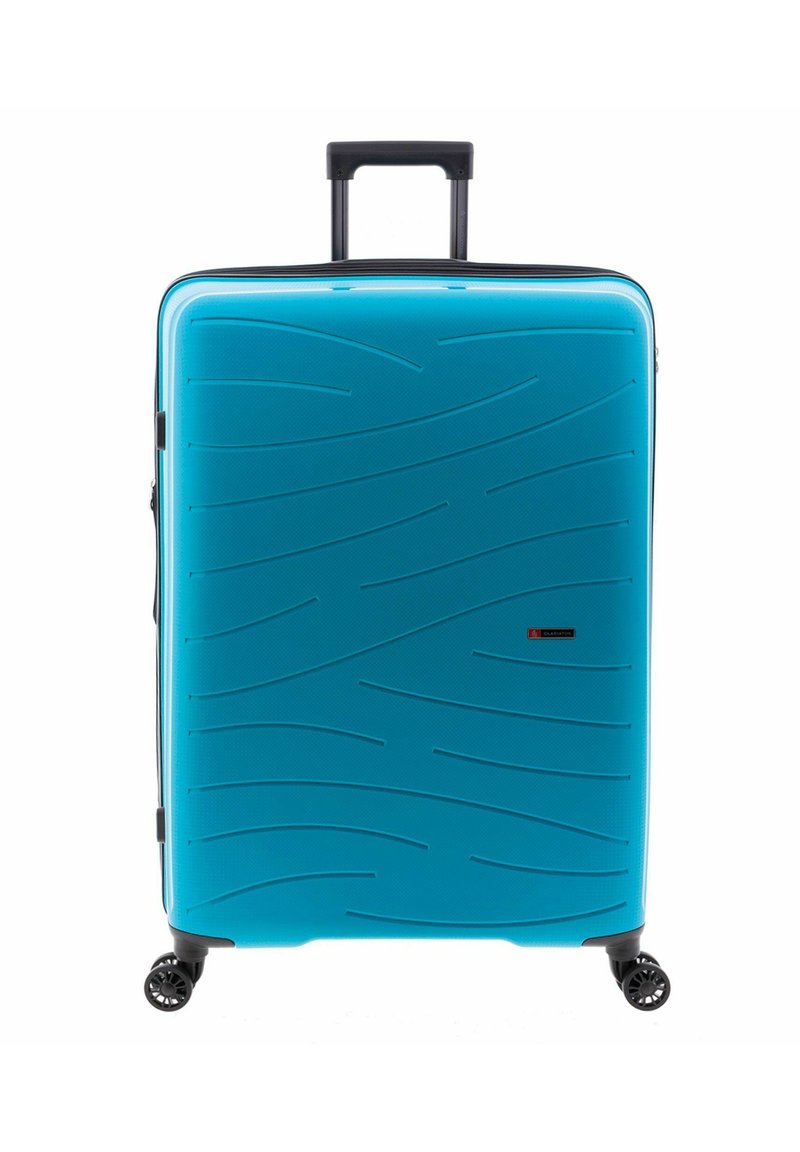 Maleta de hard-shell en un brillante color turquesa, con superficie texturizada en ondas, mango retráctil y cuatro ruedas giratorias negras.