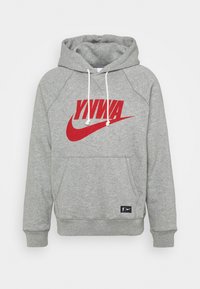 Sweat à capuche gris clair avec cordons blancs, texte rouge "YNWA" au-dessus d'un trait rouge à l'avant, et un petit patch noir près de l'ourlet.