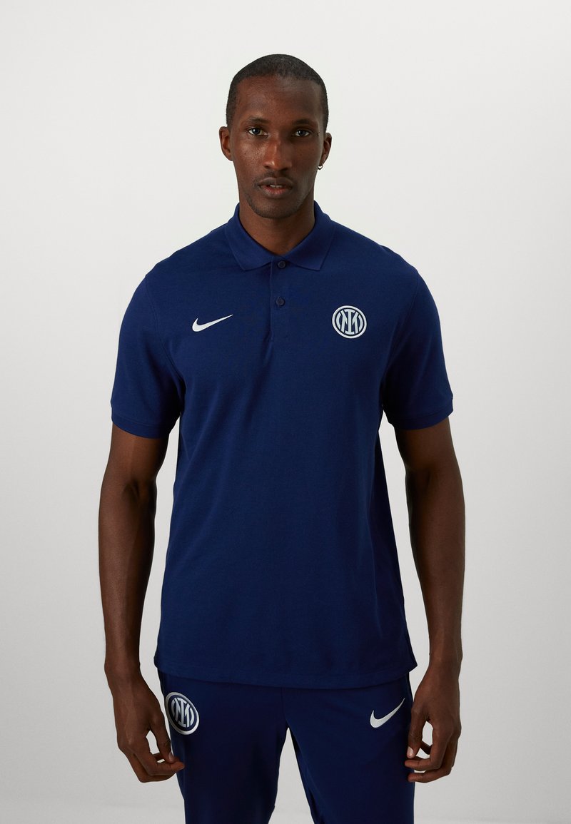 Tumesinine polo särk, mis on valmistatud puuvillast, nupuga kaeluses, Nike logo rinnal ja ümmargune tikandembleem.