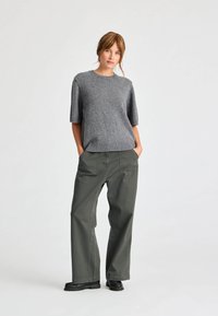 Gray knitted short-sleeve sweater with a round neckline, paired with loose-fitting olive-green pants featuring front pockets and a straight cut.