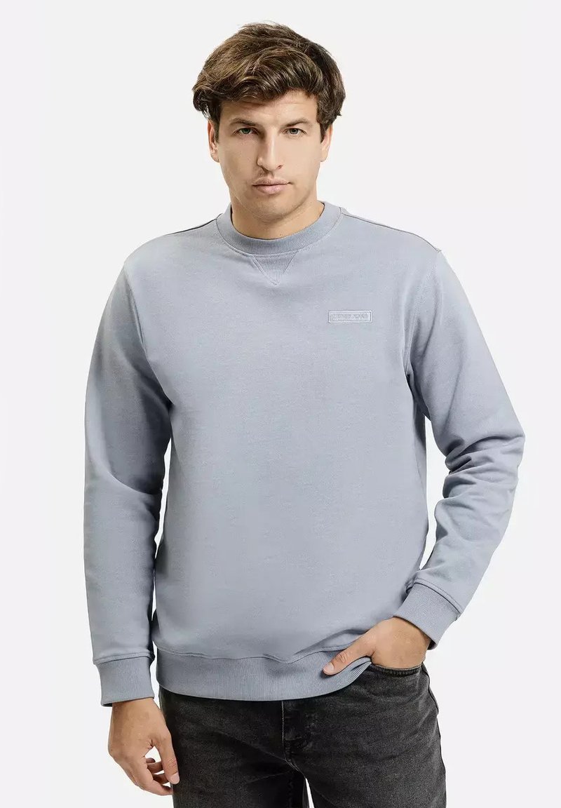 Jasnoniebieski sweatshirt wykonany z mieszanki bawełny. Posiada okrągły dekolt, ściągacze przy rękawach oraz małe logo marki na piersi. Klasyczny krój.