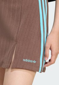 Ruske ribane kratke hlače s svetlo modrimi stranskimi črtami in majhnim belim logotipom Adidas na robu. Imajo zareze za večjo svobodo gibanja.